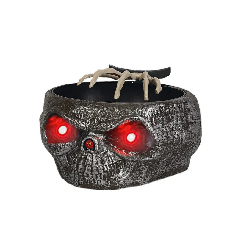Plastic Halloween pumpkin candy bowl with motion activated skeleton hand, glowing red eyes, in Khaki colour, on a table with candy.