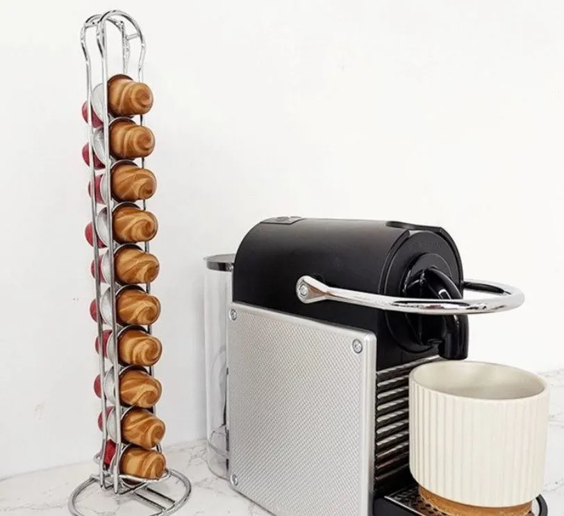 Black and silver wrought iron coffee capsule storage rack holding pods on shelves.