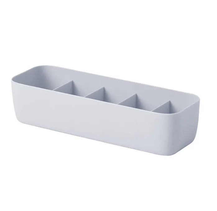 PP plastic socks and underwear storage box with grid compartments in apricot colour on a desktop