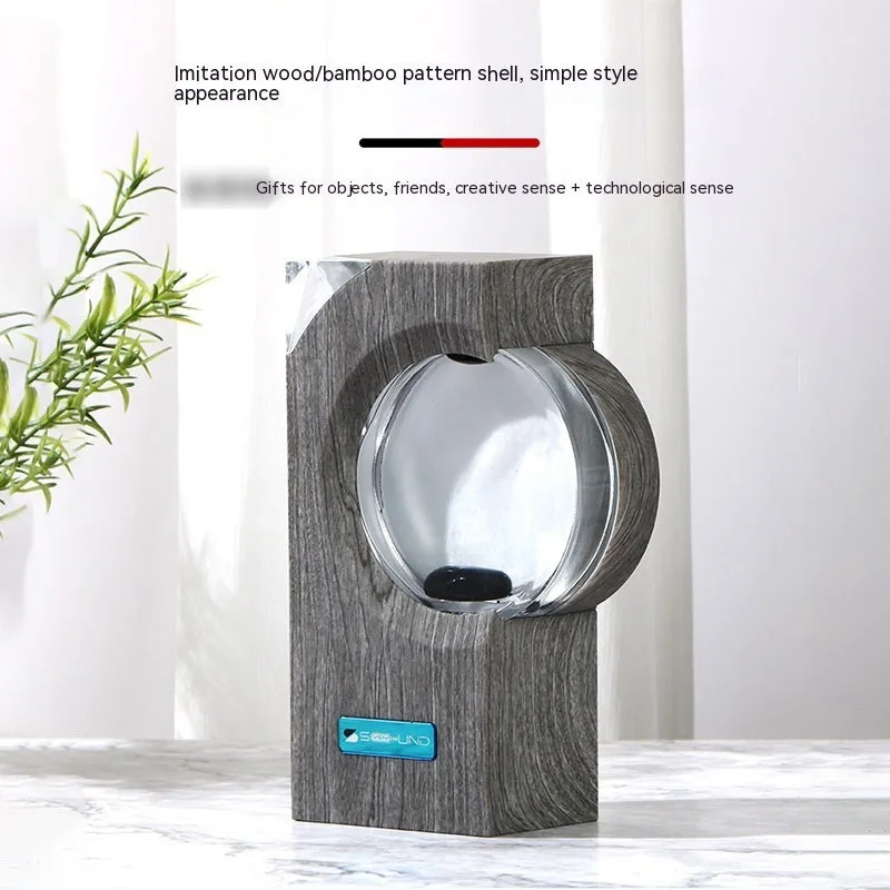 Dancing ferrofluid speaker in gray plastic casing with warm white light showing magnetic fluid shapes