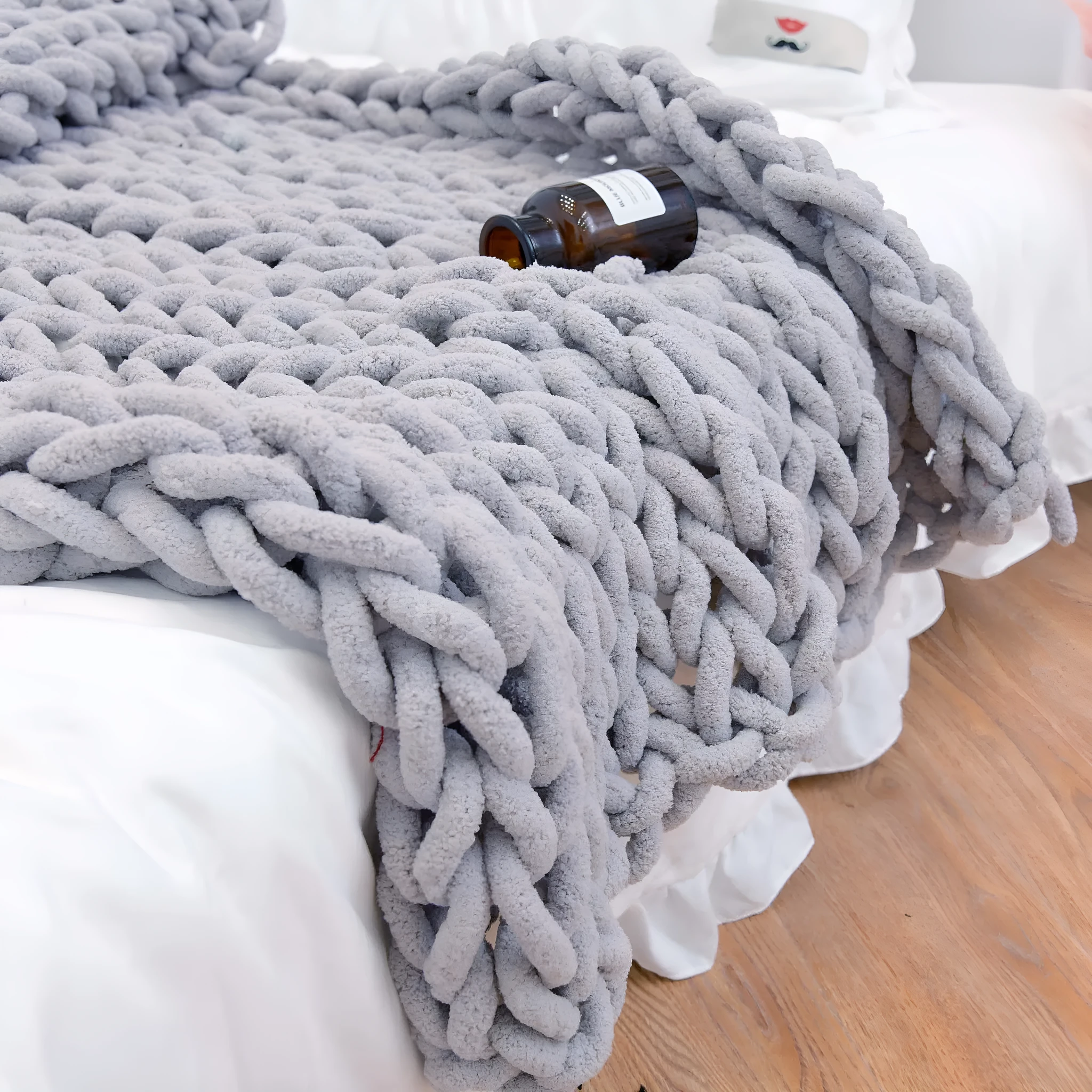 Handmade coarse yarn knitted chenille blanket with thick yarn, cable stitching, beige colour, folded decoratively