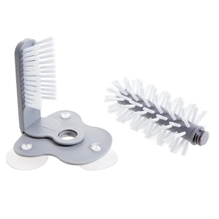 Grey 2-in-1 cup scrubber with double-sided bristles and three suction cups on a white surface