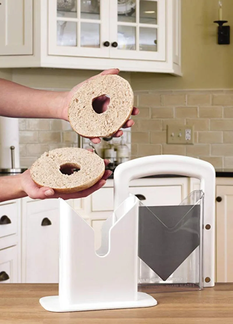 White plastic bagel slicer with acrylic safety shield and stainless steel serrated blade on a kitchen counter