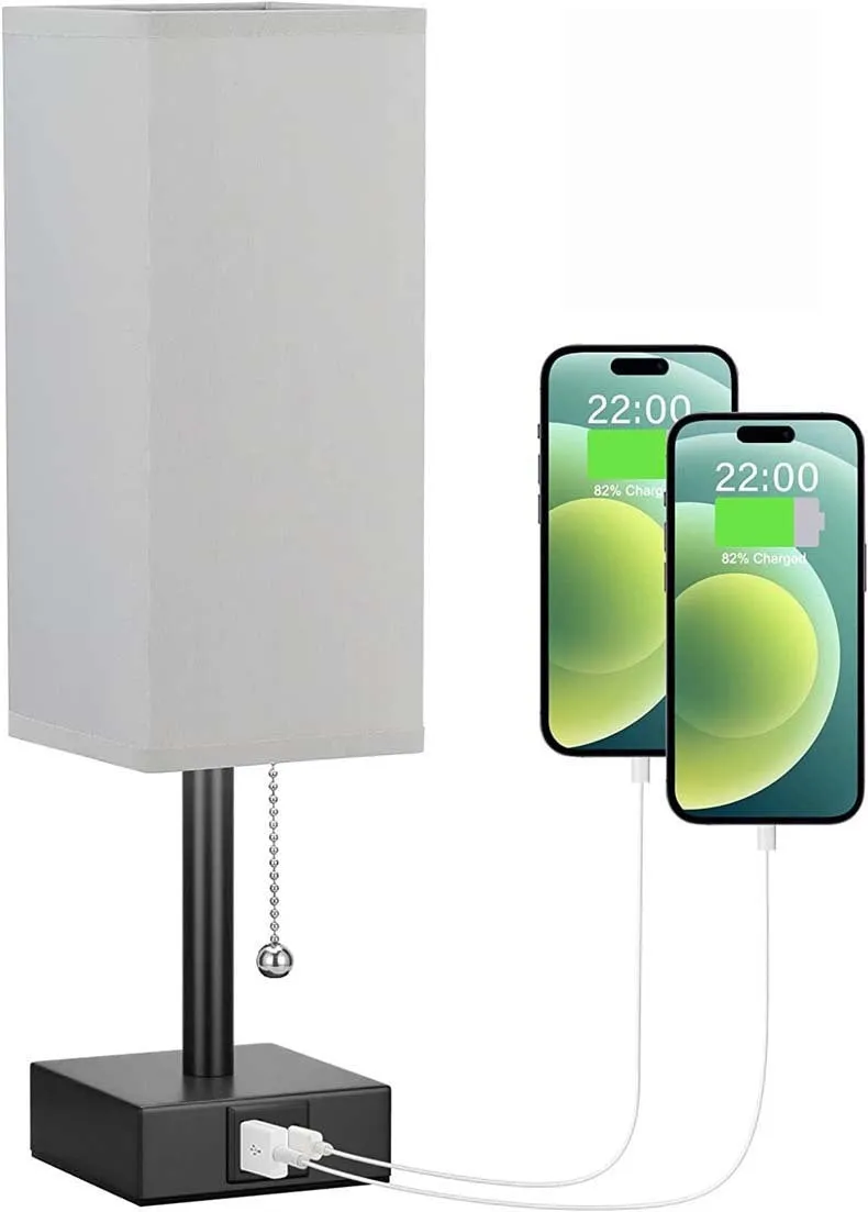 Small bedside table lamp with fabric shade and USB charging ports on a nightstand with pull chain control