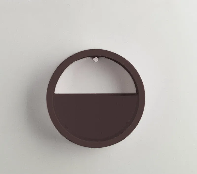 Round iron wall vase in black hanging on a wall with a succulent plant inside