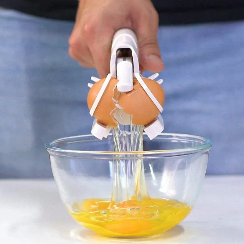 White handheld egg shell cracker with curved silicone grip and metal mechanism on a kitchen counter