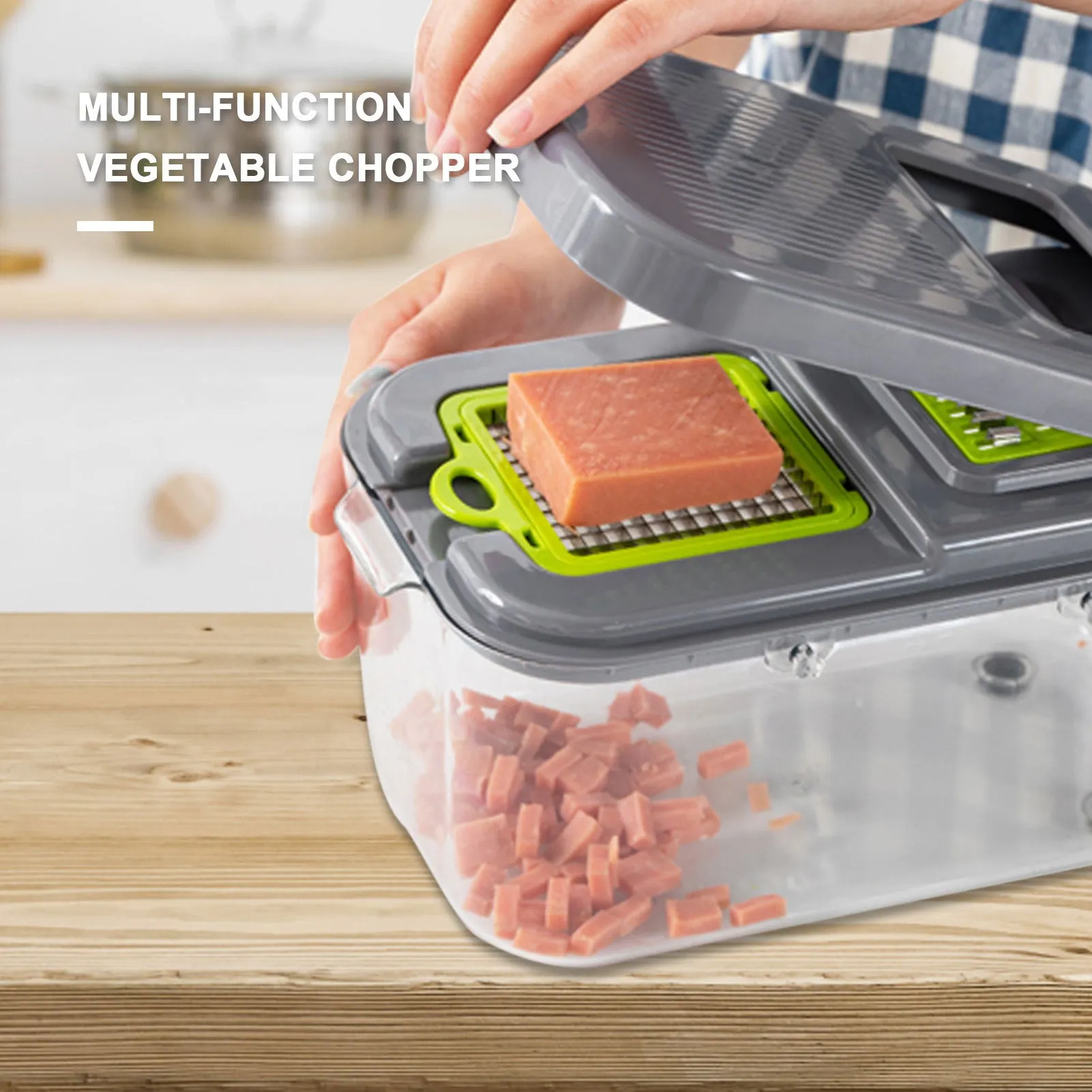 Grey multifunctional vegetable cutter with stainless steel blades, foldable compartments, and a large container on a kitchen counter