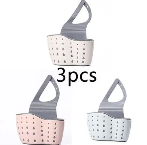 Set of three plastic kitchen sink storage racks in light blue, light pink, and beige on a countertop