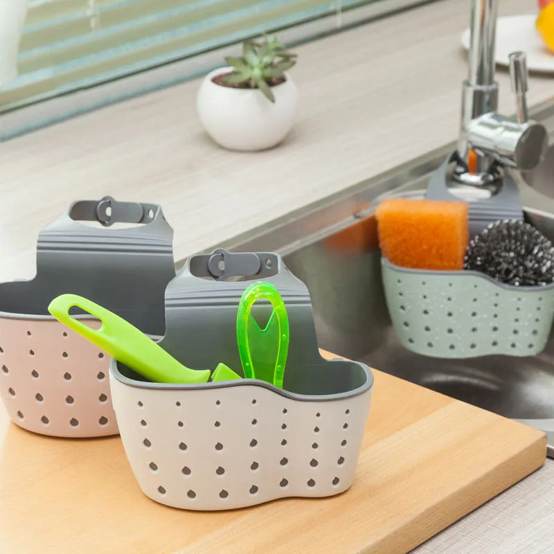 Set of three plastic kitchen sink storage racks in light blue, light pink, and beige on a countertop