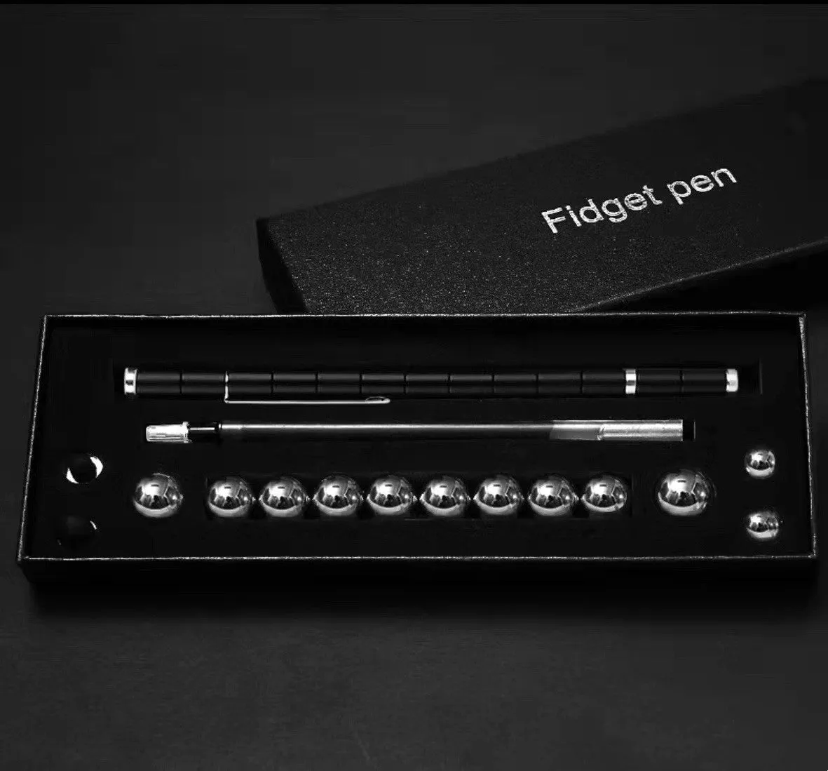 Magnetic modular fidget pen with silver finish, magnetic rings, steel balls, and capacitive head on a table