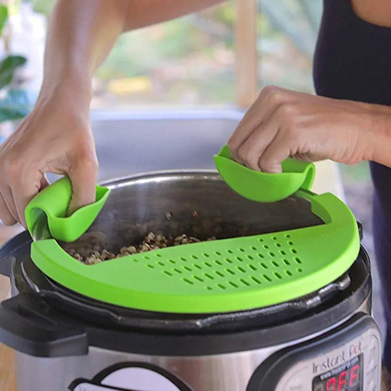 Black silicone food oil drainer snapped onto a pot rim, with liquid being poured off