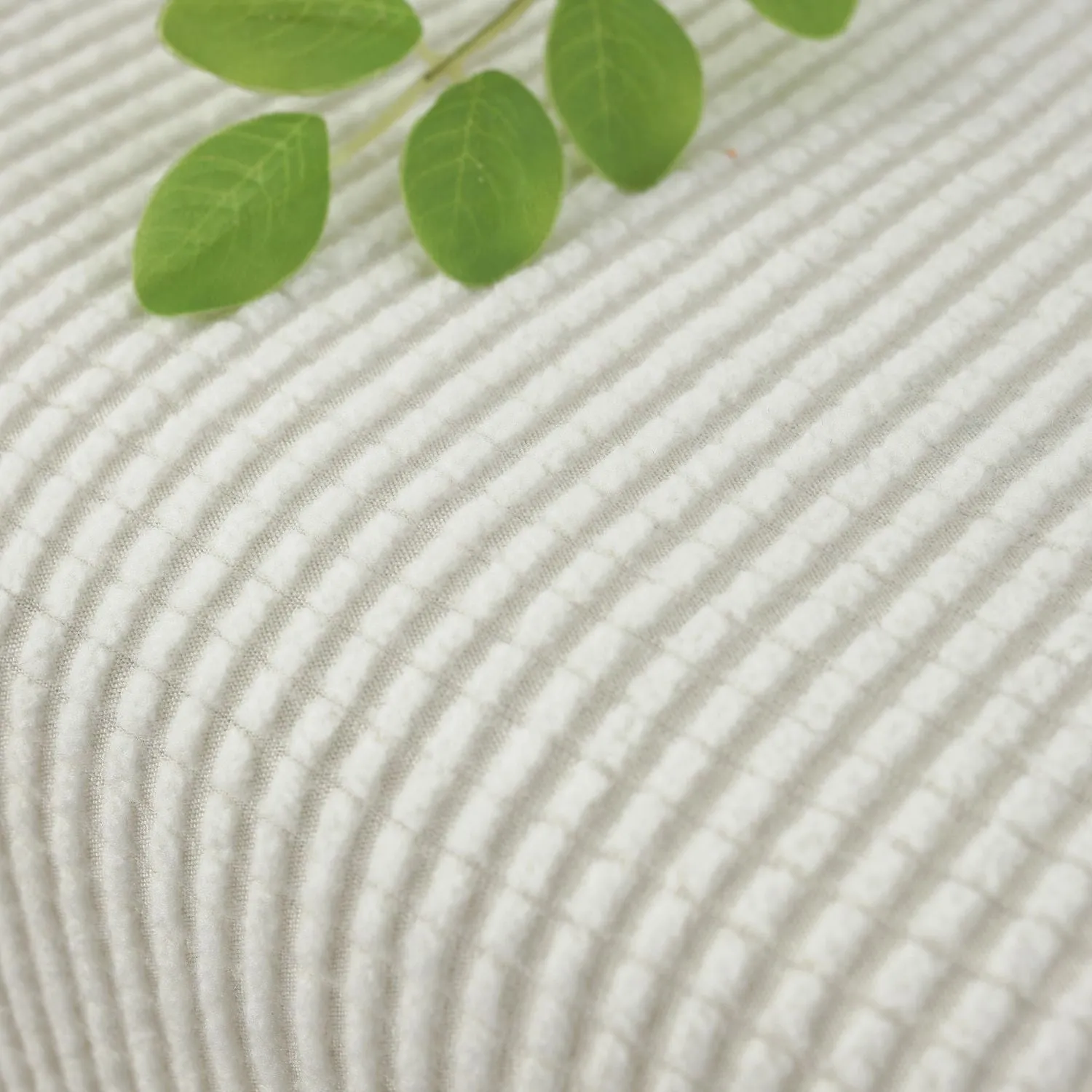 Waterproof corduroy sofa cover in beige with anti-slip elastic edges on a two-seater sofa in a living room