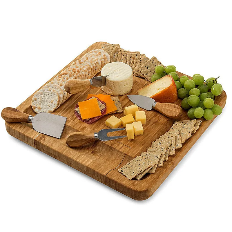 Square bamboo cutting board with drawer holding four-piece knife and fork set in wood colour