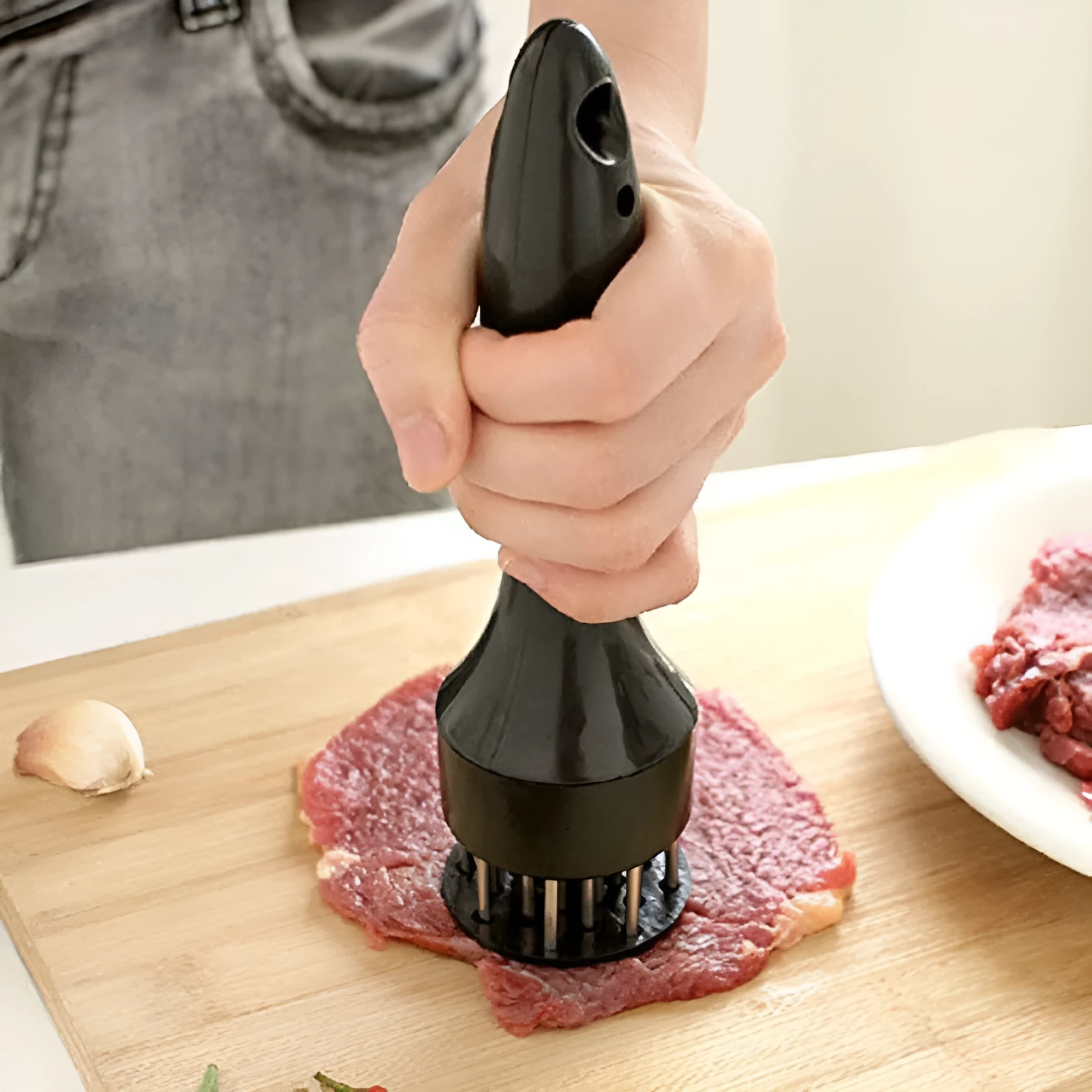 Pine meat needle tenderiser tool for steak with white handle and metal needles, shown on a kitchen surface