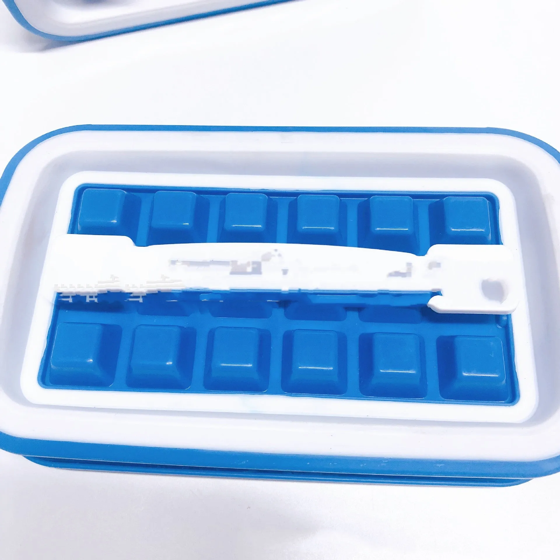 Blue silicone ice cube tray with 36 square cavities and a lid on a wooden table