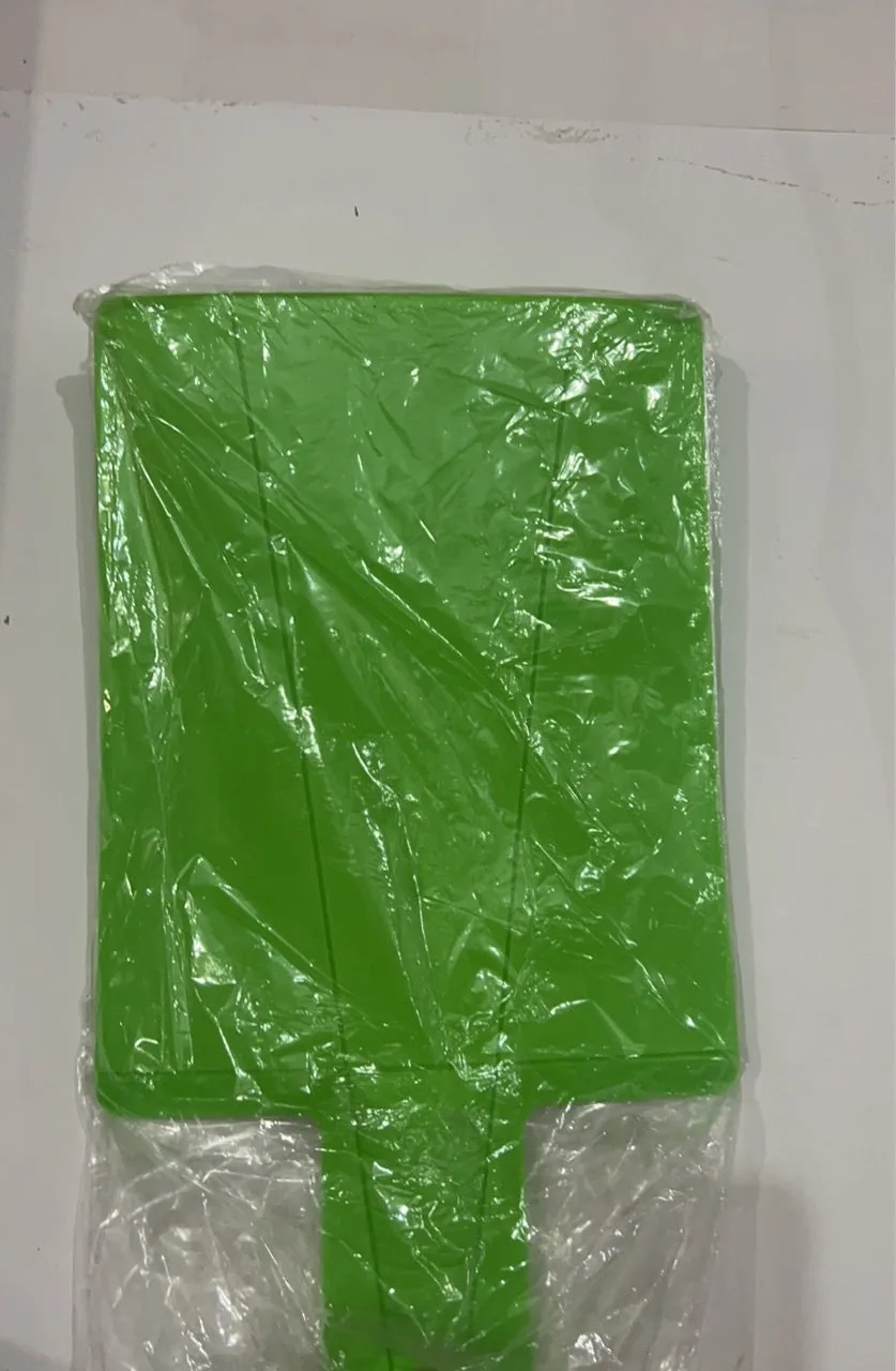 Green folding plastic cutting board with non-slip texture and hanging hole on kitchen countertop