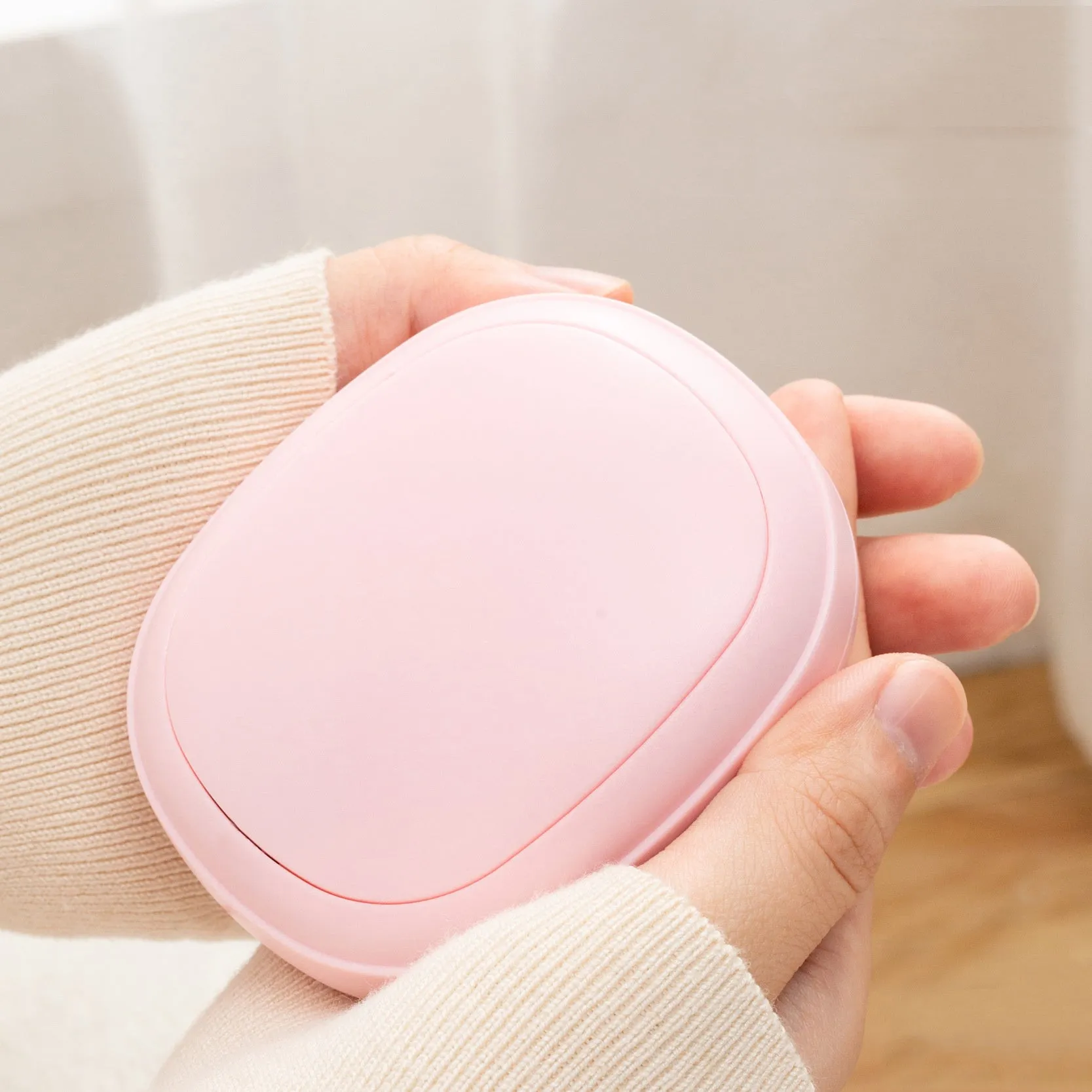 USB hand warmer in pink with three-gear temperature control and compact pebble design
