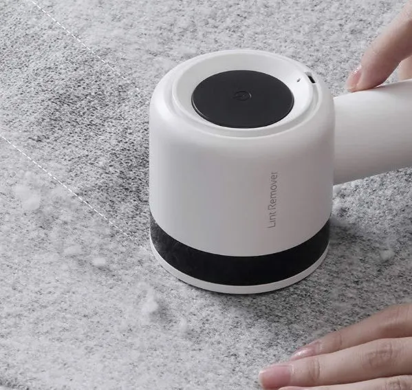 White rechargeable lint remover with hidden hair collection container and detachable three-blade head on white background