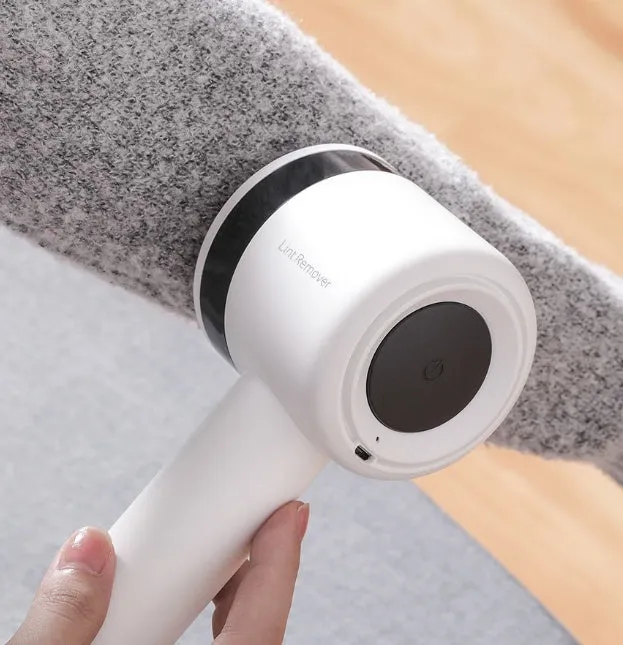 White rechargeable lint remover with hidden hair collection container and detachable three-blade head on white background