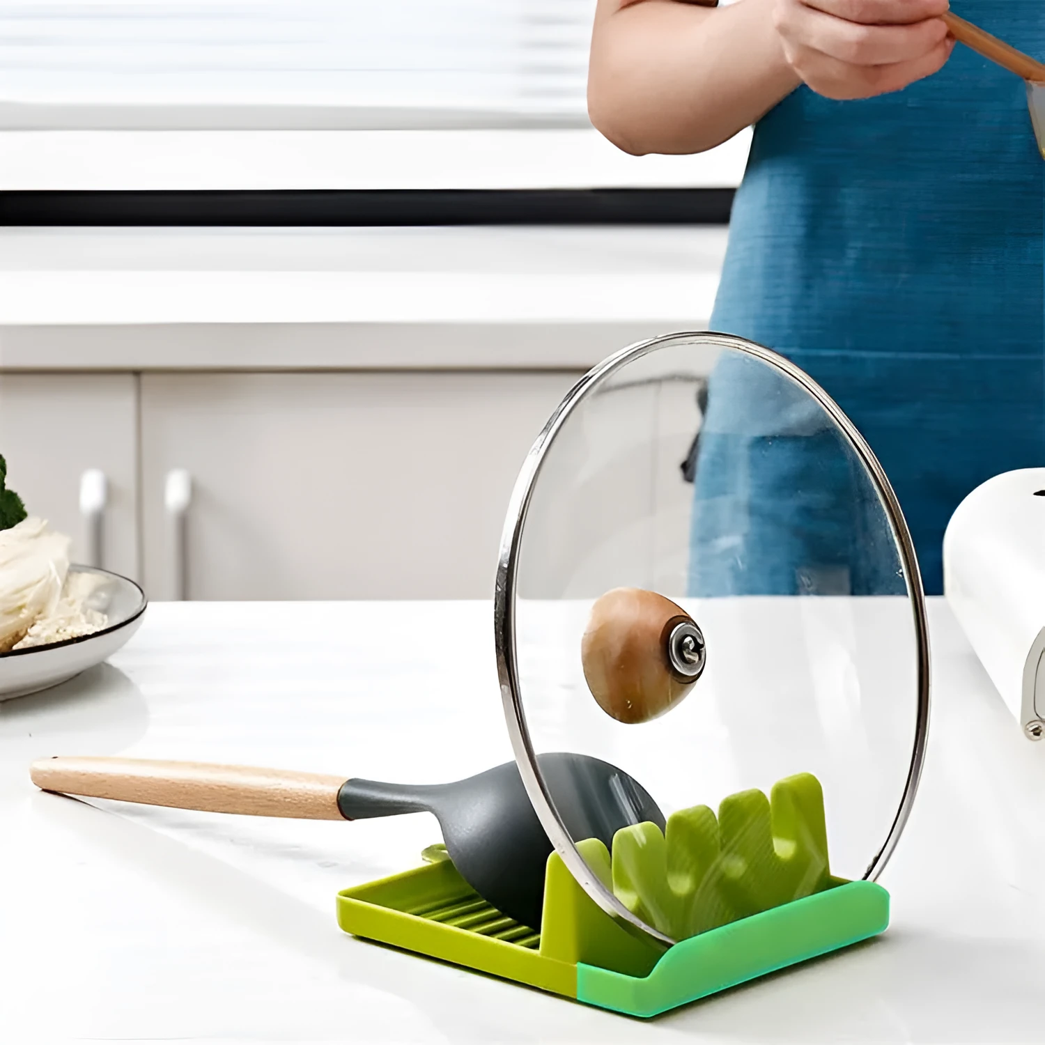 Green silicone kitchen utensil holder with four holes holding spatula, spoon, knife, and chopsticks on countertop