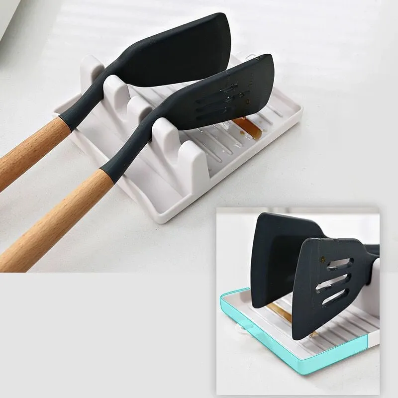 Green silicone kitchen utensil holder with four holes holding spatula, spoon, knife, and chopsticks on countertop