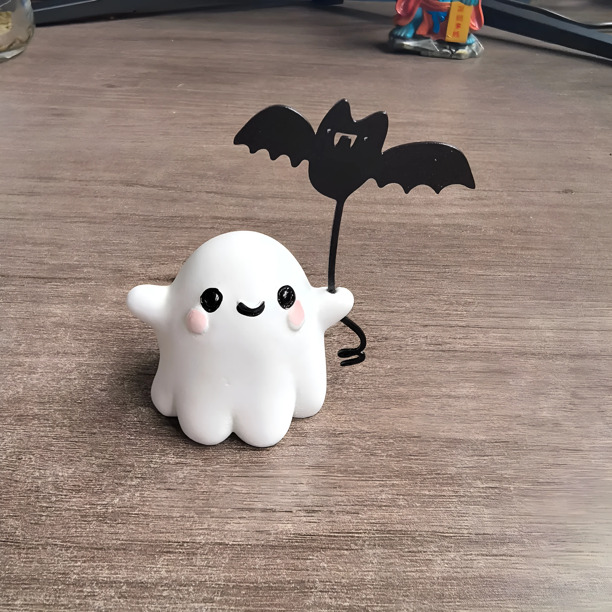 Miniature ghost walking dog statue holding a bat, a small resin Halloween ornament.