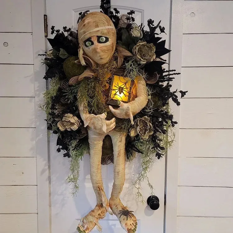 Three-dimensional mummy Halloween wreath with skeleton hands on a wooden door