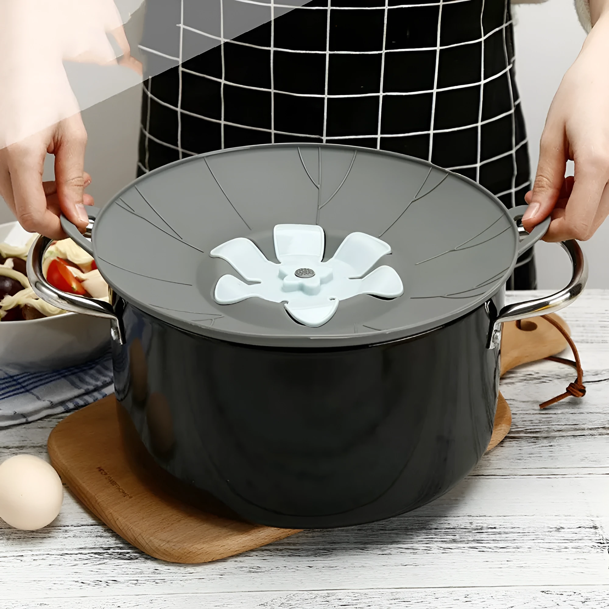 Silicone spill-proof pot cover in black, size 30x26cm, resting on a pot