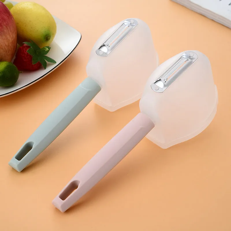 Stainless steel fruit peeler with pink PP plastic handle on a light background