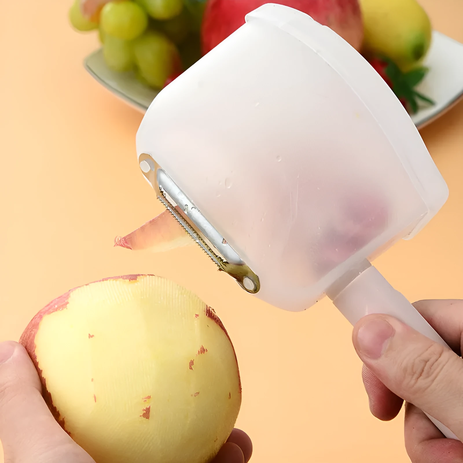 Stainless steel fruit peeler with pink PP plastic handle on a light background