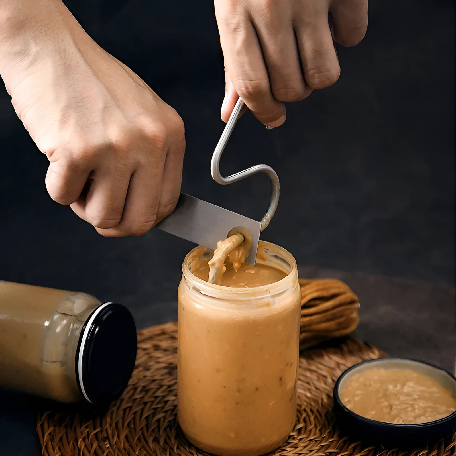 Stainless steel peanut butter mixer stirring rod on a kitchen counter with a jar of peanut butter