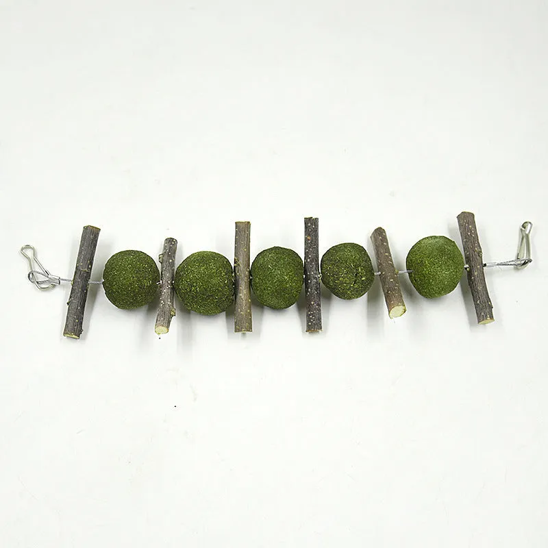 Set of five grass balls and six apple branch pet molar chew toys on a string, hanging against a plain background