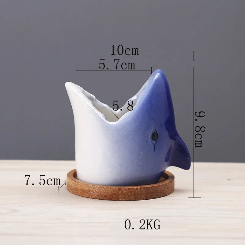 Creative cartoon ceramic succulent pot with drainage hole, blue colour, on a desk with a small succulent plant.
