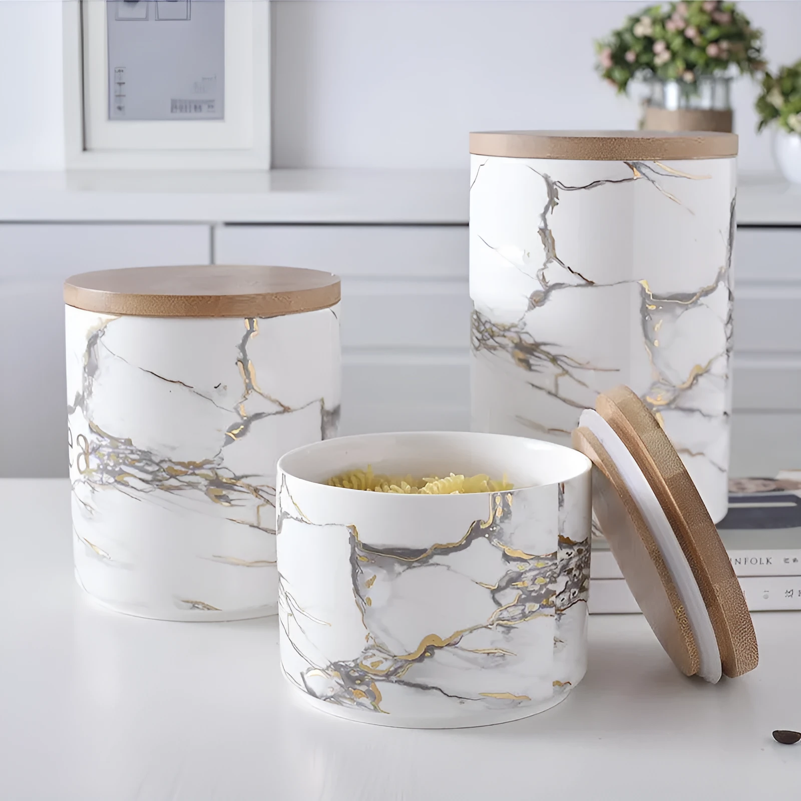 Three marbled ceramic jars with bamboo lids in large, medium and small sizes on a kitchen counter