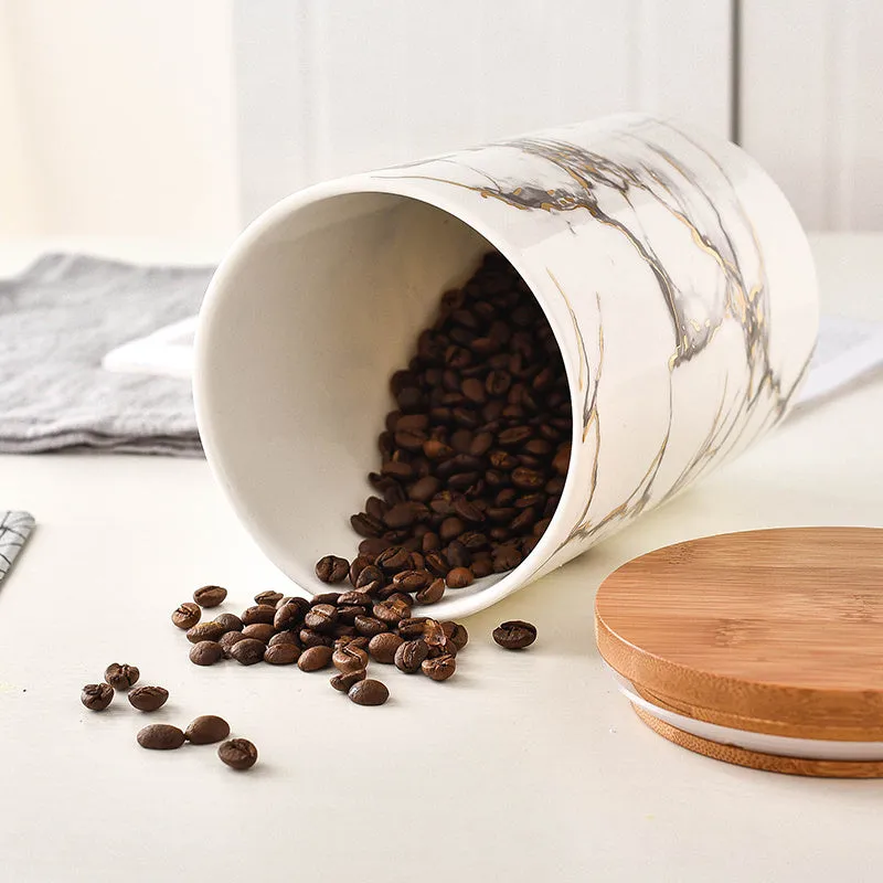 Three marbled ceramic jars with bamboo lids in large, medium and small sizes on a kitchen counter