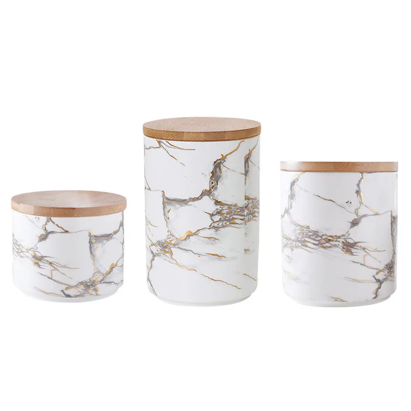 Three marbled ceramic jars with bamboo lids in large, medium and small sizes on a kitchen counter