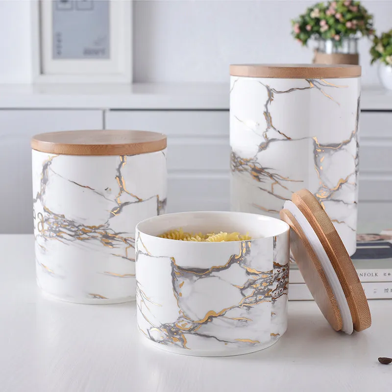 Three marbled ceramic jars with bamboo lids in large, medium and small sizes on a kitchen counter
