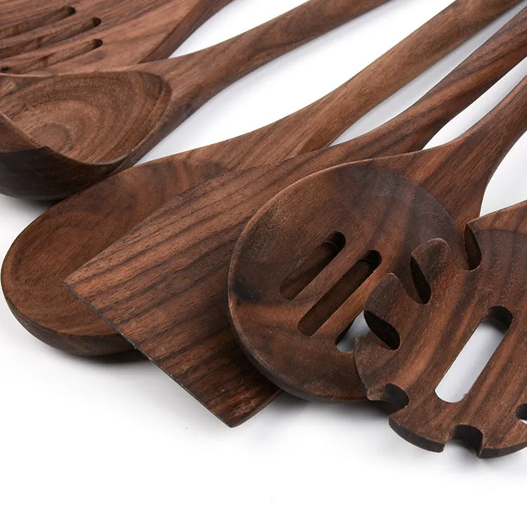 Black walnut 6-piece wooden kitchen utensil set with spatula, spoons, and spaghetti claws on a table