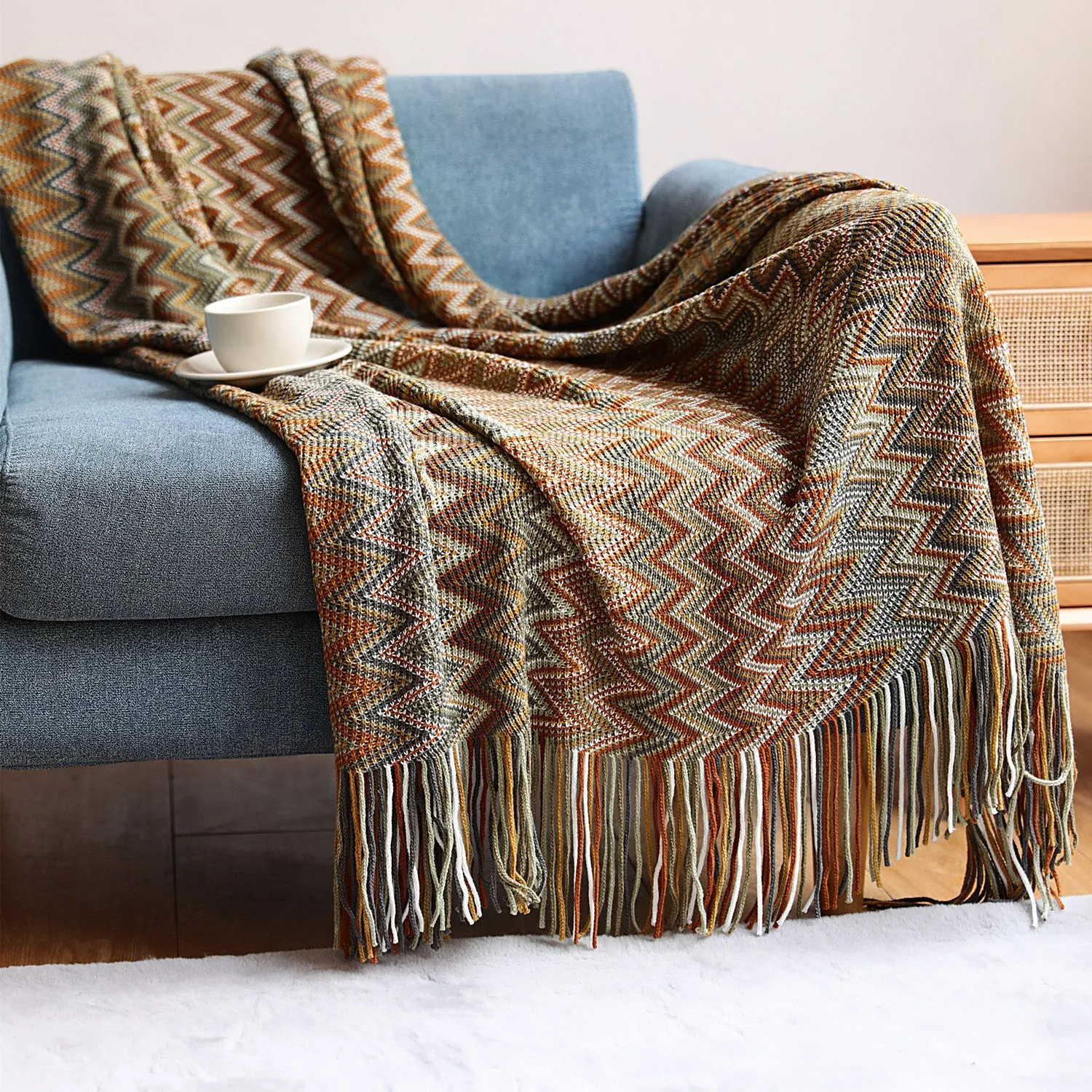 Blue knitted acrylic blanket with striped pattern and fringe, draped over a sofa