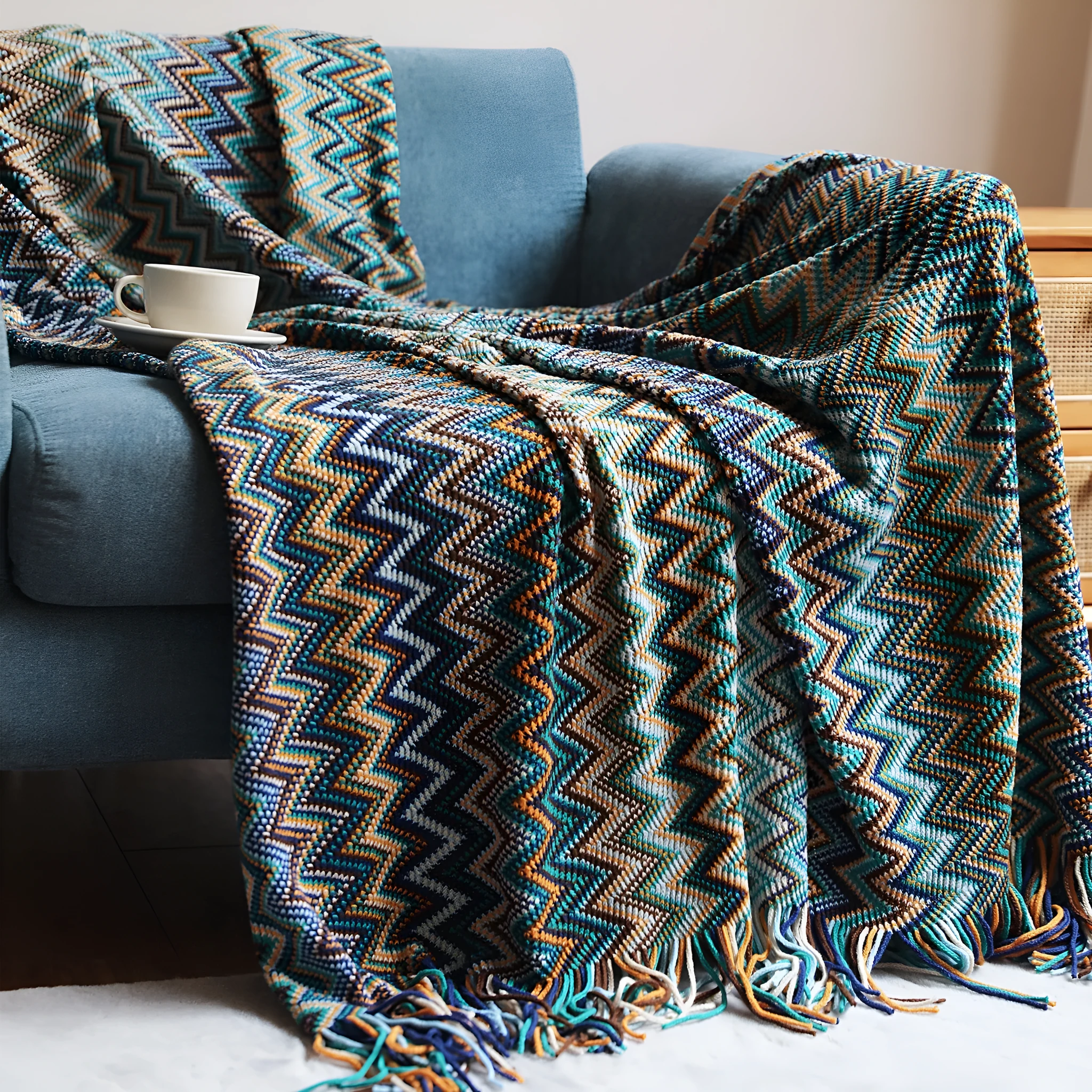 Blue knitted acrylic blanket with striped pattern and fringe, draped over a sofa