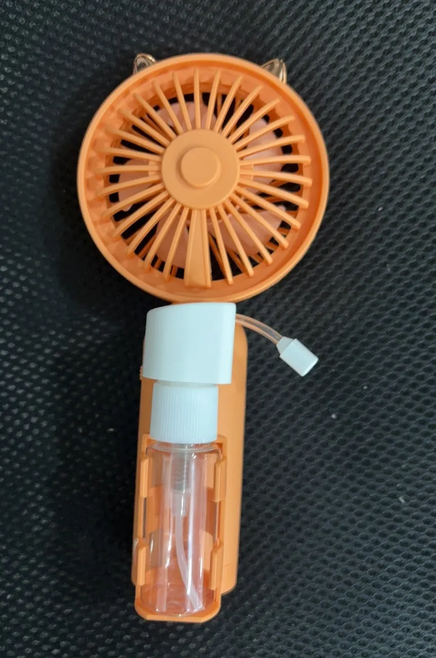 Compact plastic USB rechargeable nozzle fan in a choice of five colours on a desk.