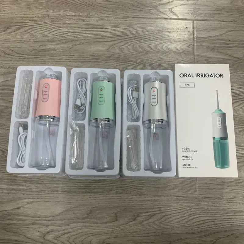 White portable oral irrigator with four nozzles and USB charging cable on a bathroom surface