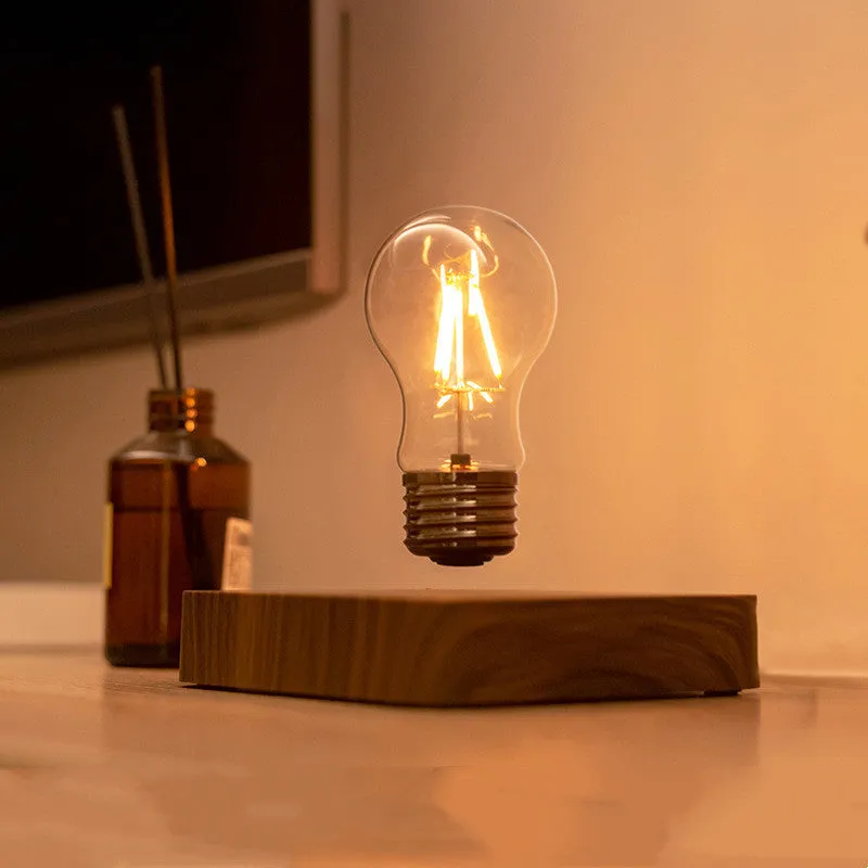 Creative minimal self-rotating maglev bulb with ABS base and warm yellow light on a desk