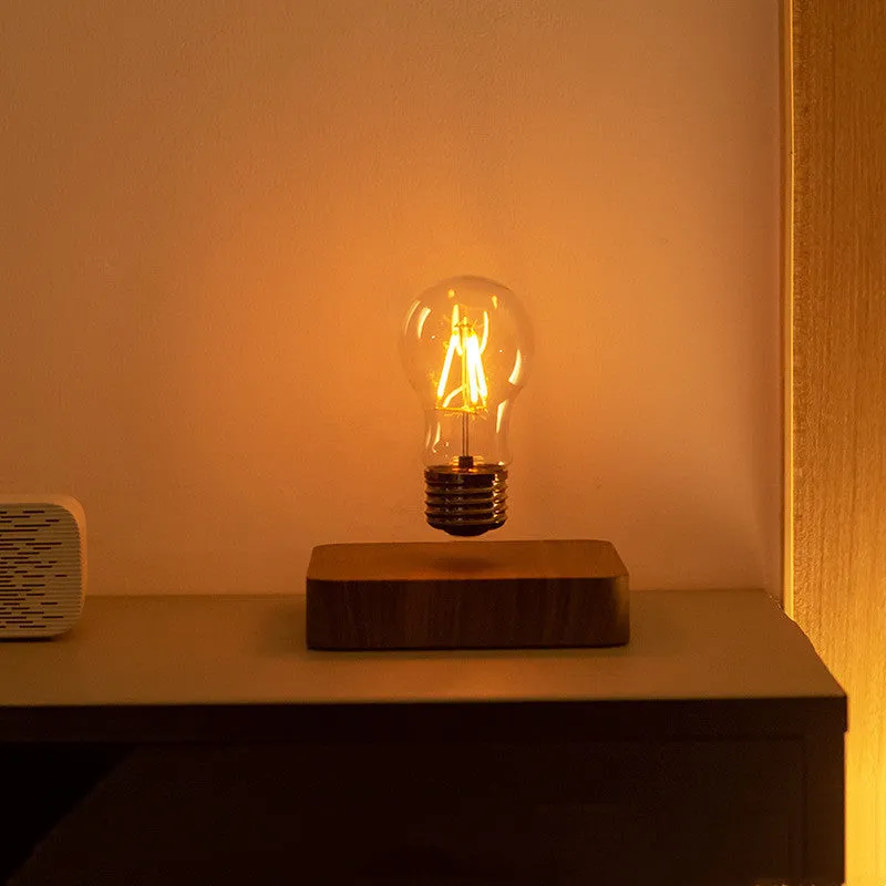 Creative minimal self-rotating maglev bulb with ABS base and warm yellow light on a desk