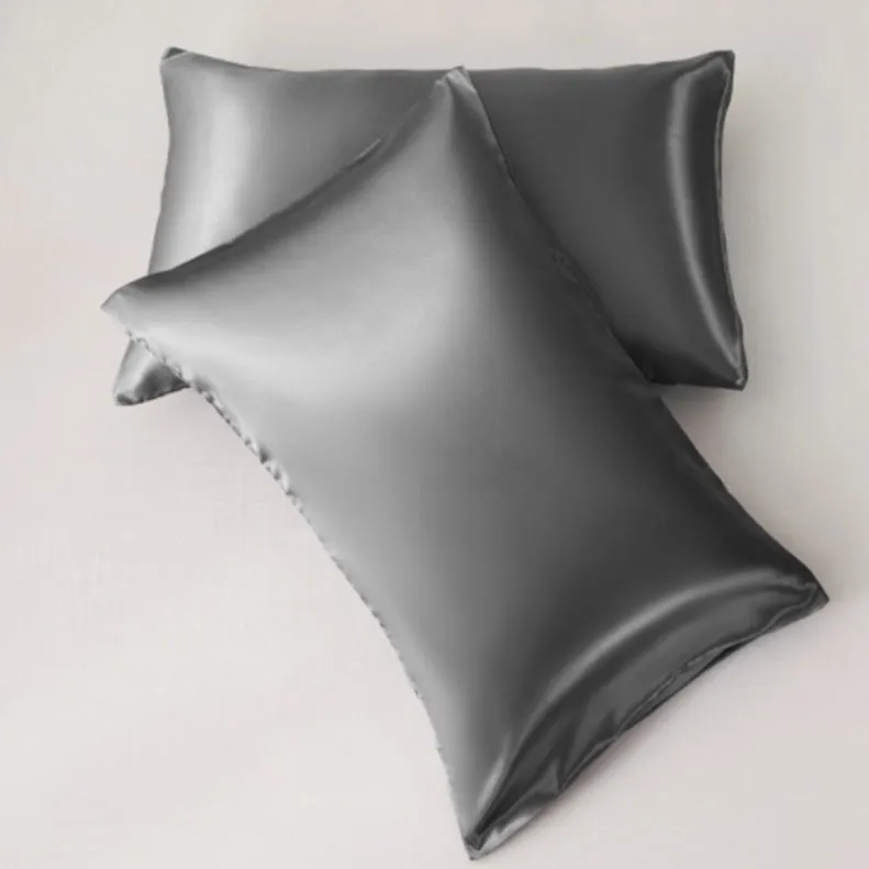 Dark blue polyester satin pillowcase with envelope closure on a bed with white sheets