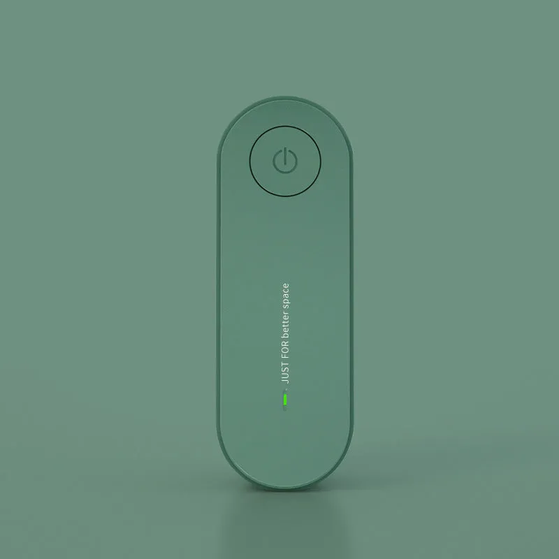 Small negative ion air purifier in black, plugged into a wall socket, with a room in the background