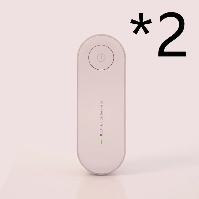 Small negative ion air purifier in black, plugged into a wall socket, with a room in the background