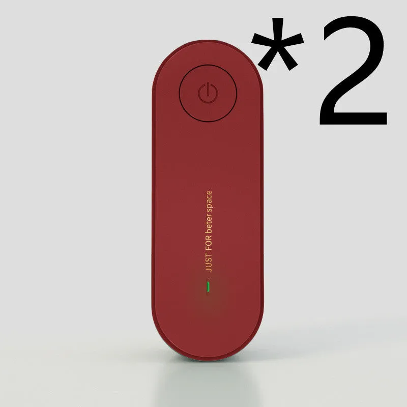 Small negative ion air purifier in black, plugged into a wall socket, with a room in the background