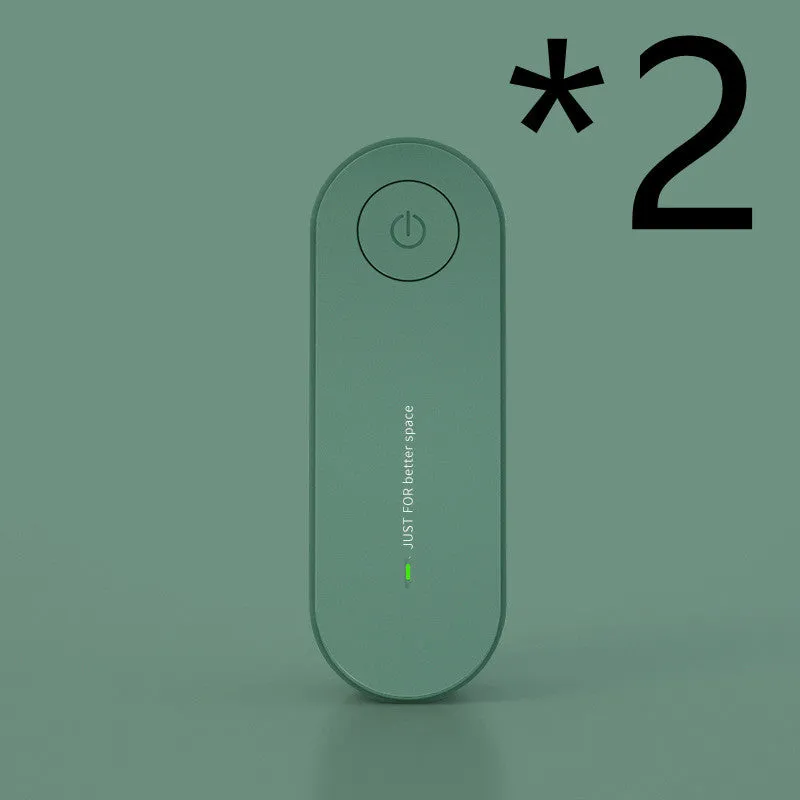 Small negative ion air purifier in black, plugged into a wall socket, with a room in the background