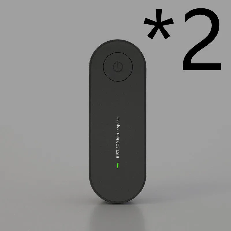 Small negative ion air purifier in black, plugged into a wall socket, with a room in the background